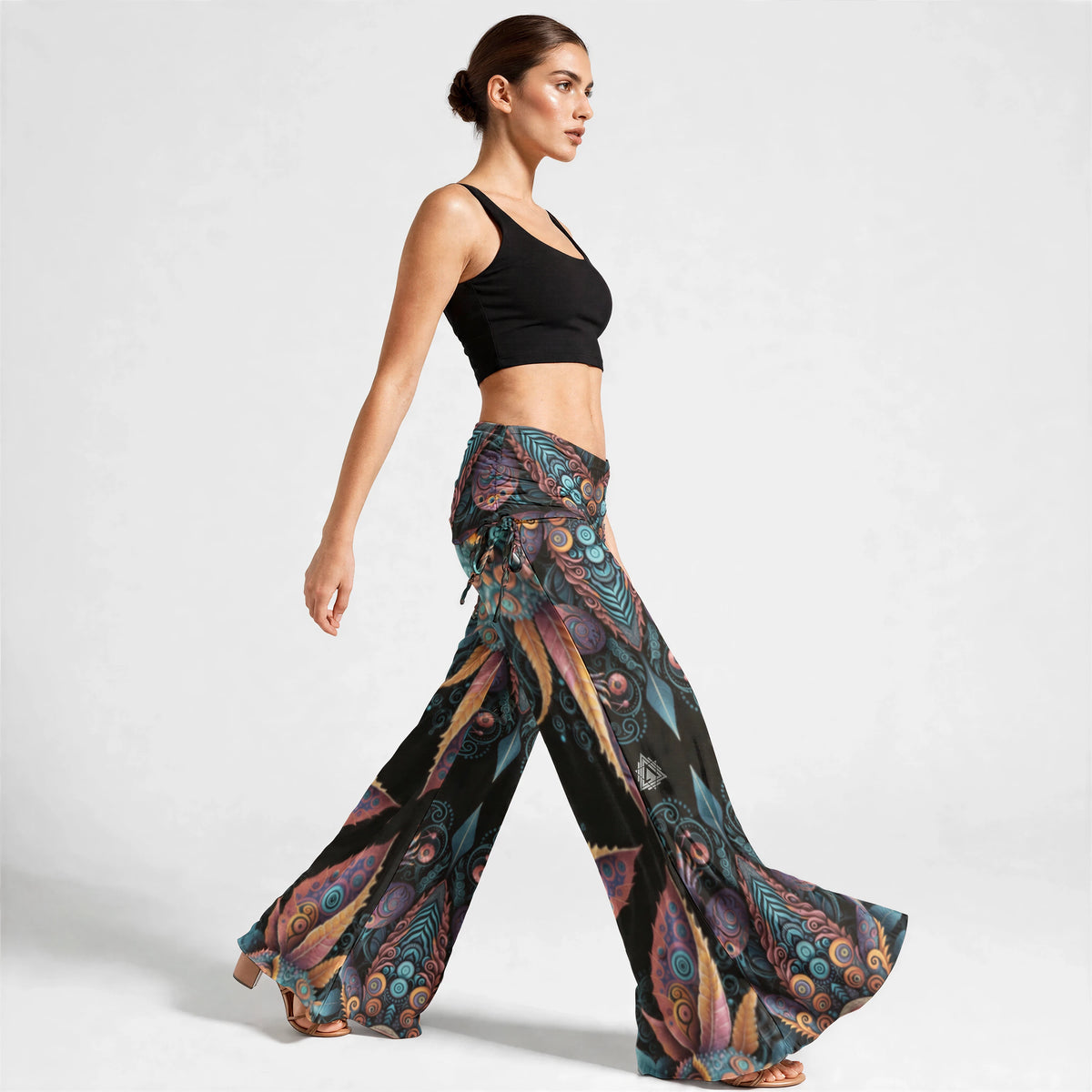 Three-quarter view of the wide leg pants showing the ruched waistband and left thigh emblem print.