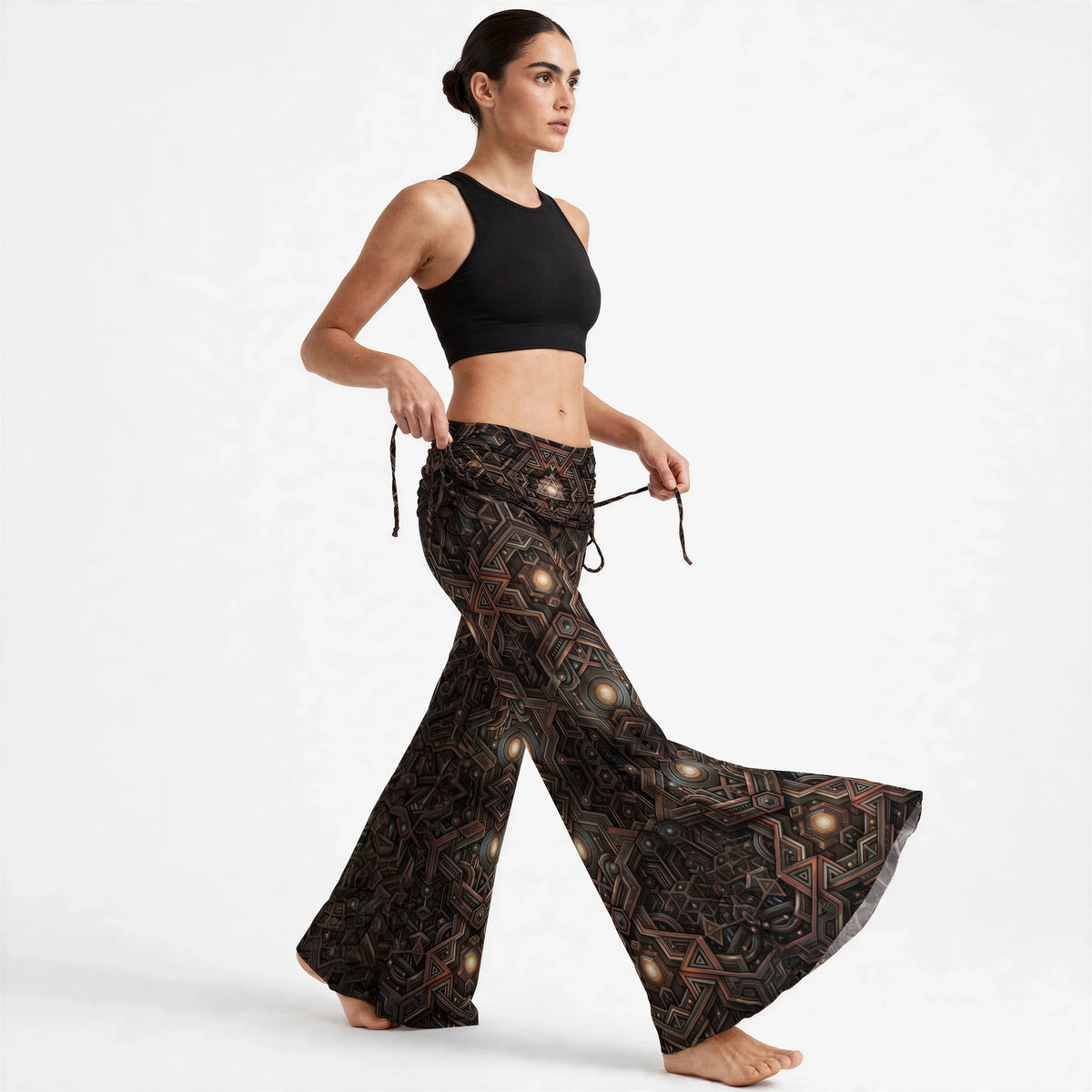 (Front three-quarter) Front three-quarter view of wide leg pants with a bronze, teal and black geometric mandala print and gathered high waistband.