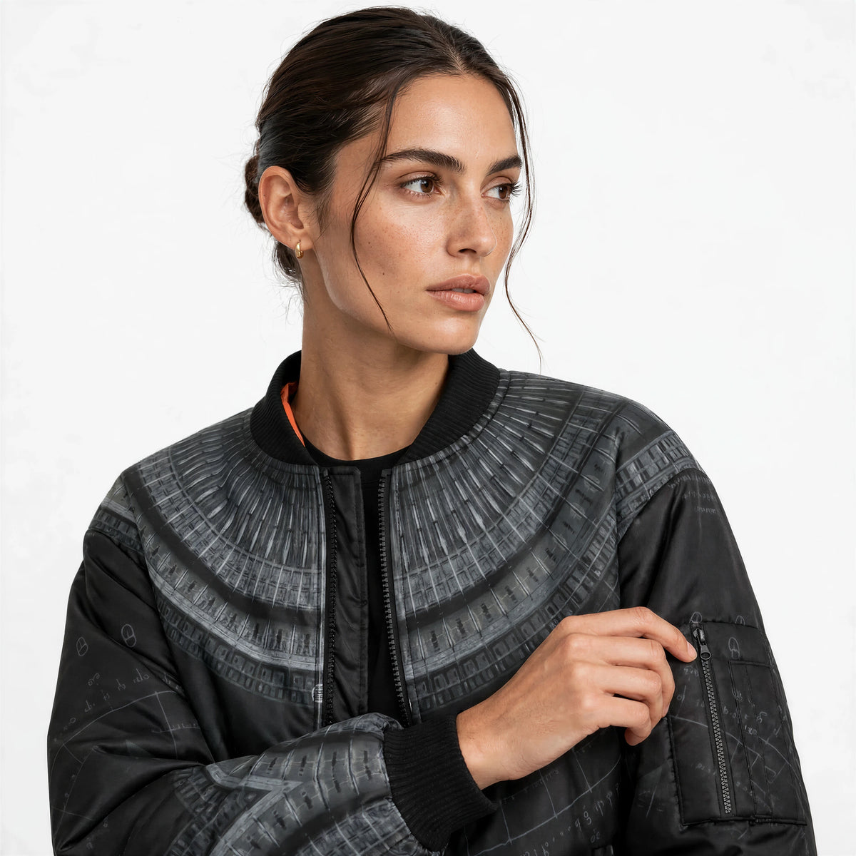 Close-up of the jacket's upper front and sleeve, showing the radiating print detail, ribbed collar and orange inner lining.
